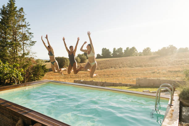 istock Female friends jumping into the pool 2097084372