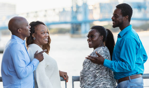 Two African-American couples converse on city waterfront