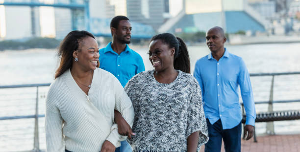 African-American friends walk, talk on city waterfront