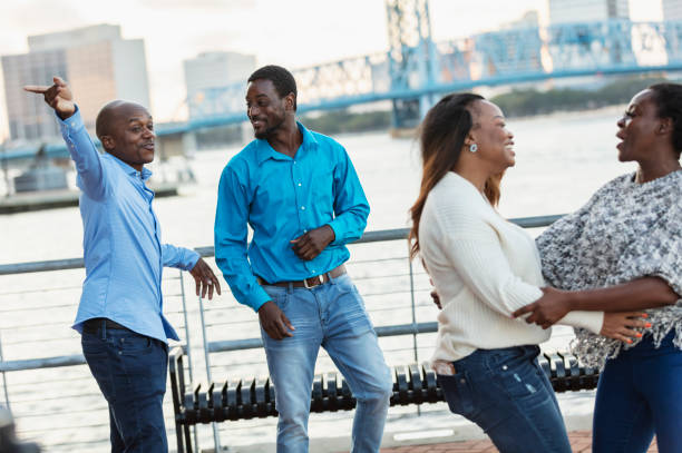 Two African-American couples converse on city waterfront