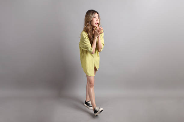The Asian woman in casual dressed standing on the grey background.