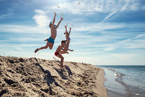 Happy teen in red jumping on the beach a sunny day