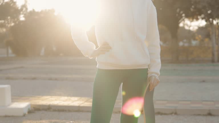 Silhouette girl with skateboard in park against backdrop sunset. Sun dip below horizon,creating picture scene tranquility and leisure.