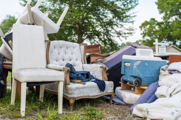Pile of Abandoned Household Items on Curb A cluttered collection of household items, including upholstered chairs and a vintage cooler, sits abandoned on a suburban curb, illustrating themes of waste, moving day, or garage clearance. obsolescence stock pictures, royalty-free photos & images