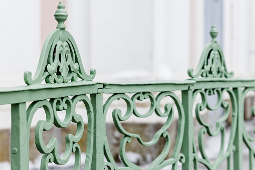 Decoration design elements of an outdoor vintage green forged railings, close up photo with selective soft focus