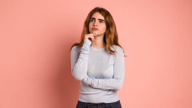 istock Pensive young woman looking up in pink studio 2097170274