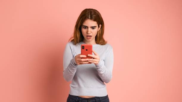 istock Surprised woman using smartphone in pink studio 2097170545