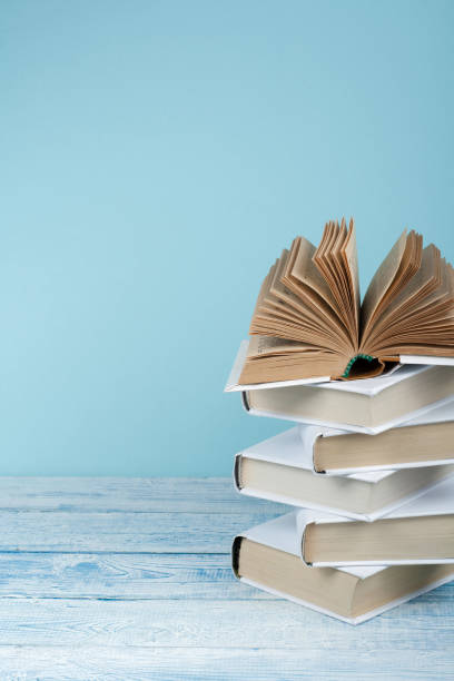 istock Book stacking. Open book, hardback books on wooden table and blue background. Back to school. Copy space for text. 2097171862