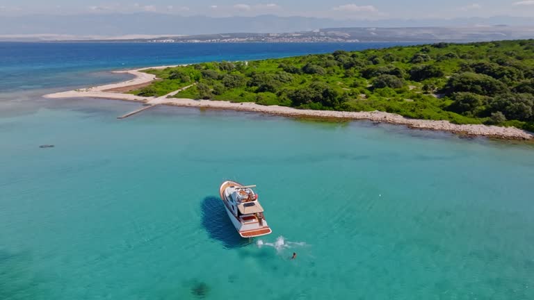 AERIAL Around a yacht and people swimming in the crystal clear sea