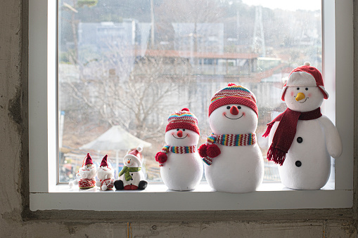 christmas snowman doll on a window frame.