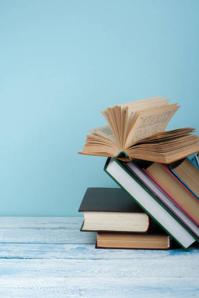 istock Book stacking. Open book, hardback books on wooden table and blue background. Back to school. Copy space for text. 2097175035