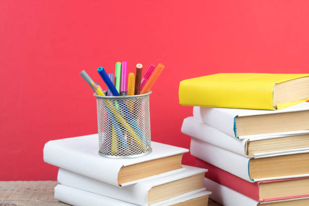 Books stacking. Books on wooden table and red background. Back to school. Copy space for ad text