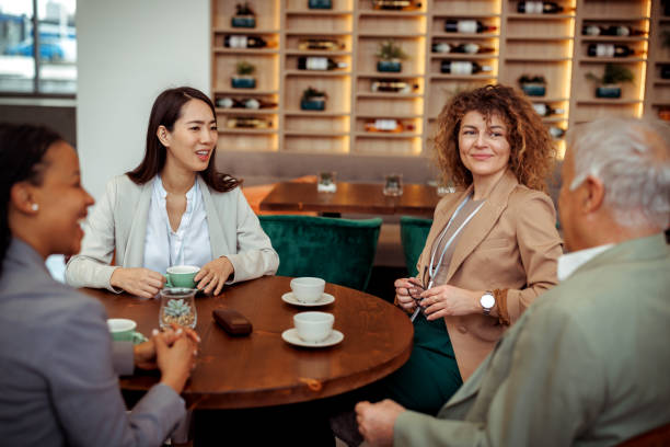 Group of well dressed business people casually talking at restaurant during coffee break