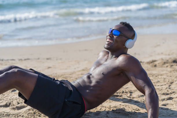 Shirtless latin brazilian backpacker tourist building a hot tub / swimming pool with a shovel on a sunlit beach in New Zealand, soaking up the joys of summer holidays while enjoying the warm ocean breeze and scenic views