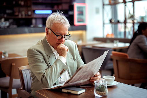 Shot of a handsome man reading a newspaper on a coffee creak in a cafe