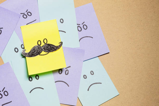 istock Yellow sticky note with a smiley face and mustache stands out against a pile of notes with angry and sad faces. Be yourself, be different. Image with copy space. 2097206694