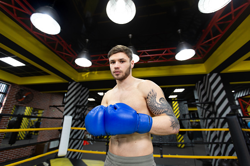 Young sporty man boxing with punching ball in boxing ring. Combat sport and healthy lifestyle concept.