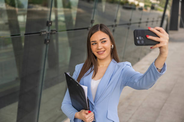 istock Woman in formal clothes  taking a selfie and sending it as a  text message while  walking near the business building. 2097244008