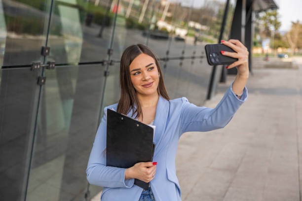 istock Woman in formal clothes  taking a selfie and sending it as a  text message while  walking near the business building. 2097244517