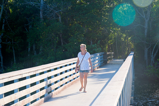 Blonde woman on a boardwalk at the nature preserve four miles cove at the Caloosahatchee river in Cape Coral, Florida, USA.