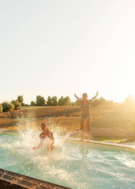 istock Female friends jumping into the pool 2097269833