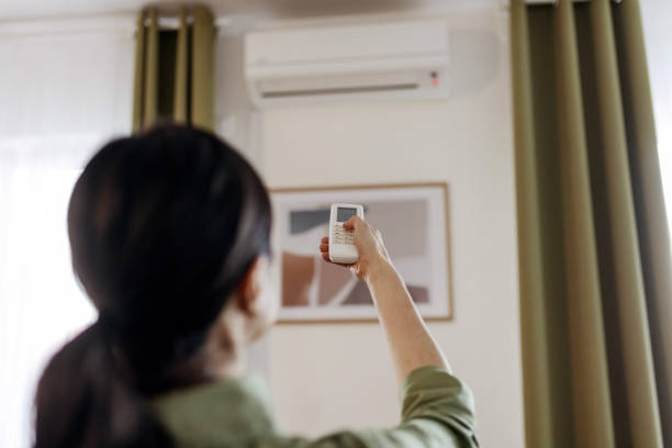 istock Woman Control Aimed at the Air Conditioner 2097281723