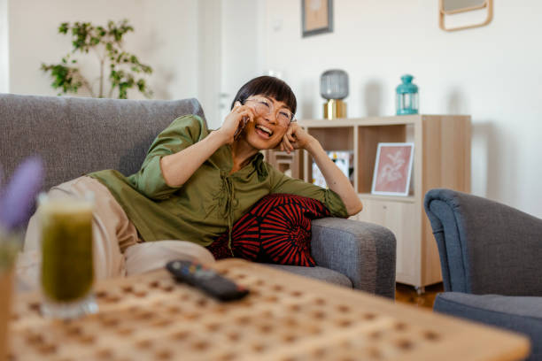 istock Woman Talking on the Phone While Relaxing on Her Cozy Sofa at Home 2097282767