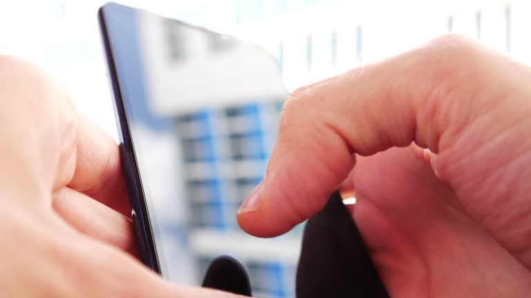 Close-up of two male hands holding a smartphone and typing a message outdoors