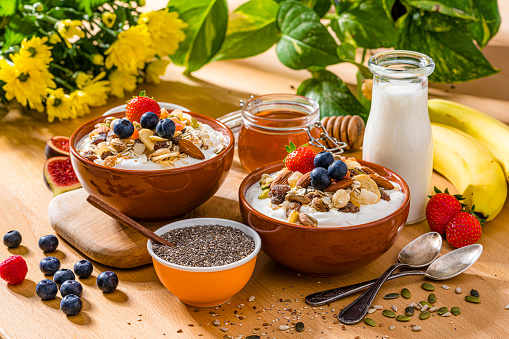 Breakfast table served with healthy granola bowls, yogurt, fruits and seeds