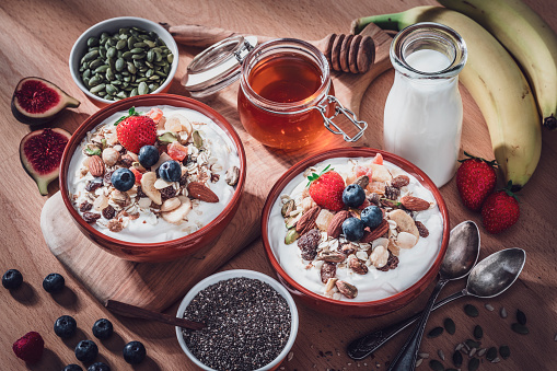 Two granola bowls, fruits and seeds on breakfast table