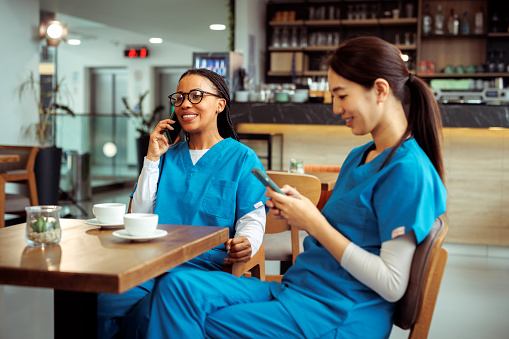 Medical workers using their smart phones while having a break at cafeteria