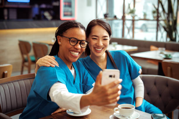 istock Medical workers taking selfie with smart phone while having coffee break at cafeteria 2097328235