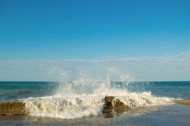 Waves crash on the pier. Water splashes, drops, splash. Marine background. Beautiful seascape.