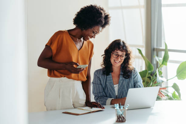 istock Two professional women collaborating happily over laptop in modern office 2097329791