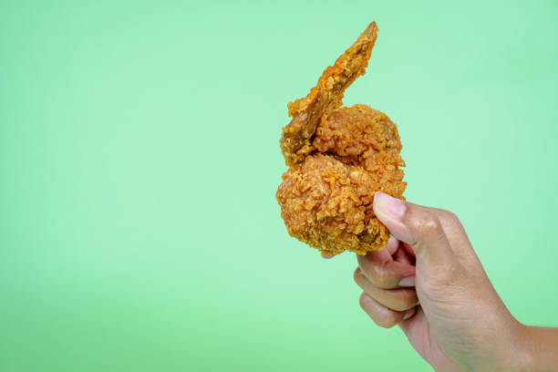 istock Female hand holding fried chicken on green background. 2097333491