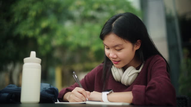 Asian girl taking note on book.