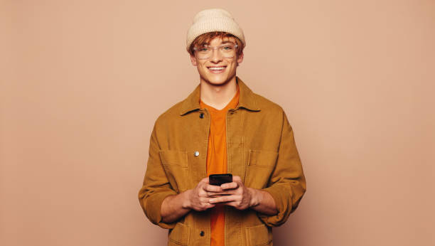 istock Casual man on peach background using smartphone 2097369568