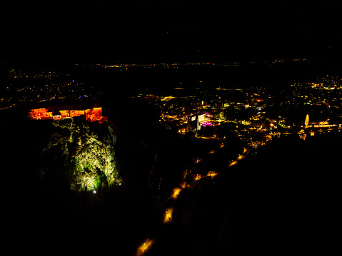 Scenic view of illuminated Lake Bled waterfront with Bled Castle and the town. Aerial view. Long line of street lights. Date: 19.12.2023, Bled, Slovenia.