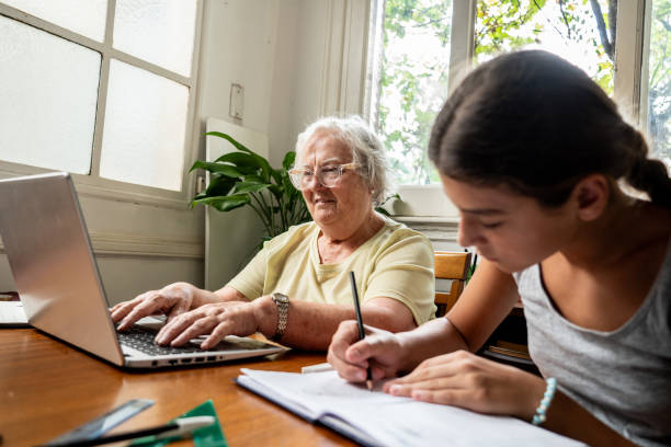 istock Grandmother using laptop and granddaughter doing homework at home 2097424113
