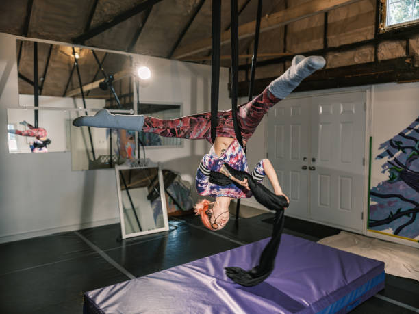Young female aerial silk performer at practice. She is dressed in casual clothing. Interior of Aerial Silk Studio inside private gym in Toronto, Canada.