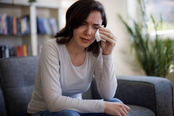istock Young woman sitting on sofa and crying 2097483649