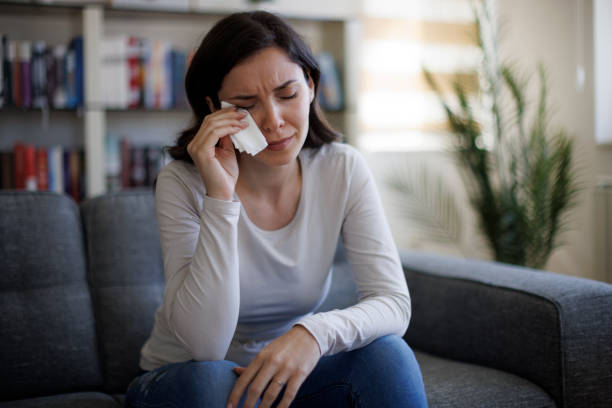 istock Young woman sitting on sofa and crying 2097483657