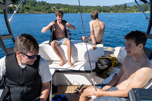 Youthful life on the lake as young individuals practice wakesurfing from a boat.