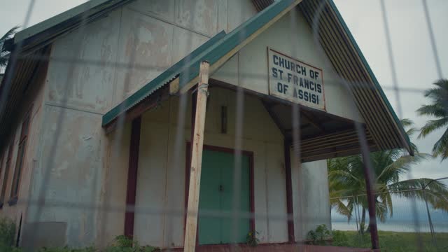 An abandoned and weathered beachside Church on a gloomy day, showing the front entrance.  Slow, right to left movement.