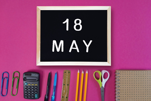 Calendar date 18th of May on chalkboard on pink blurred school stationery background. Event schedule date. School, study, education concept. Month of spring.