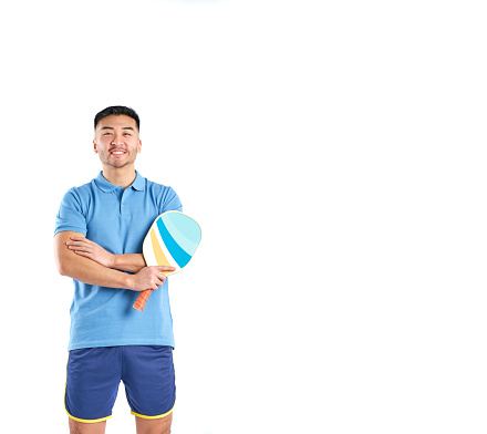 young asian man smiling in shorts and blue polo shirt with a pickleball paddle in hands on white background