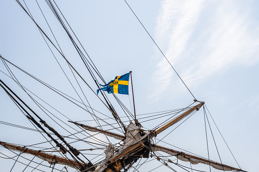 Gothenburg, Sweden - June 03 2023: Swedish flag flyig on a indiaman replica sailship.