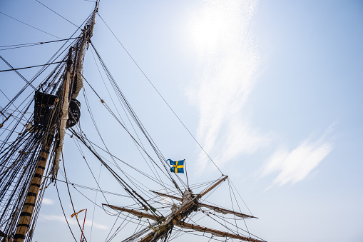 Gothenburg, Sweden - June 03 2023: Swedish flag flyig on a indiaman replica sailship.