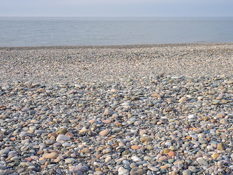 Gray sand and stones   on the beach.     Beach in winter. Sea coast soil. Beach resort atmosphere
