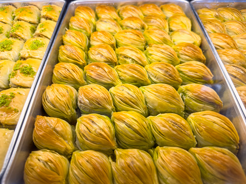 Tray full of fresh seashell shaped baklava with pistachio in a retail display